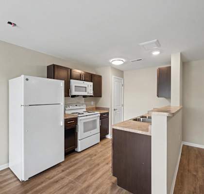 A kitchen with white appliances and wooden cabinets.