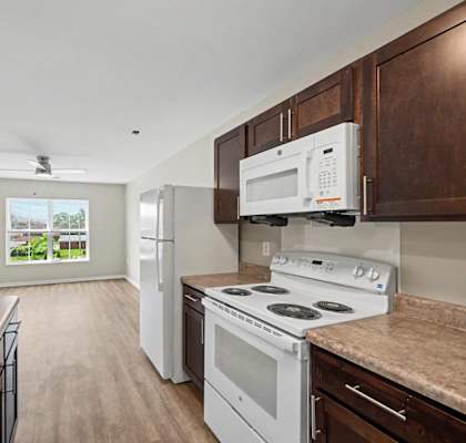 A kitchen with white appliances and wooden cabinets.