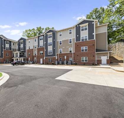 A large apartment complex with a parking lot in front.