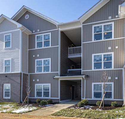 A modern two-story apartment building with a balcony on the second floor.