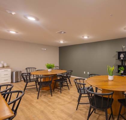 A dining room with a wooden table surrounded by chairs.