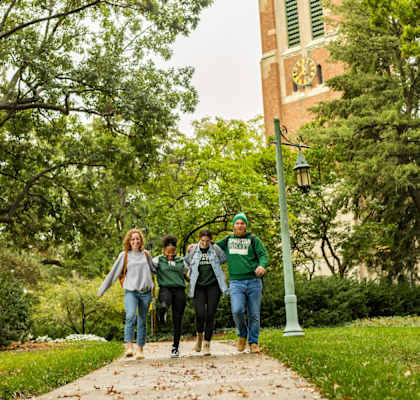 a group of people walking down a sidewalk on a college campus