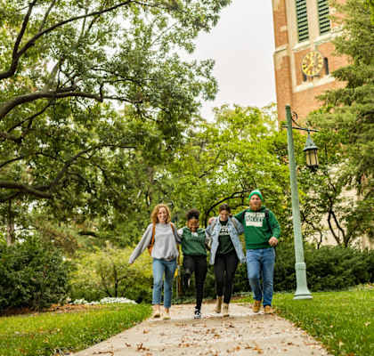 a group of people walking down a sidewalk on a college campus