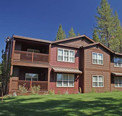 a large brown house with trees in the background