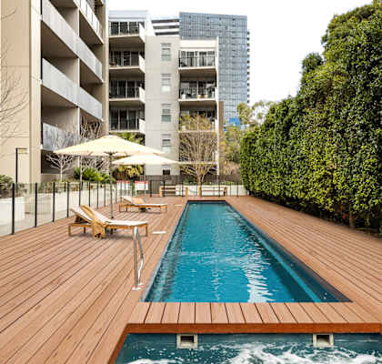 a swimming pool on a wooden deck next to an apartment building