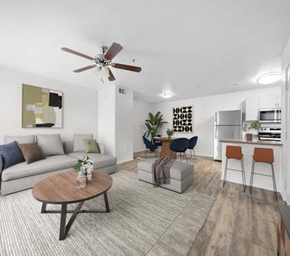 A living room with a grey couch, a coffee table, and a ceiling fan.