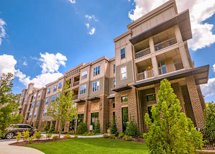 A large apartment building with a car parked in front.