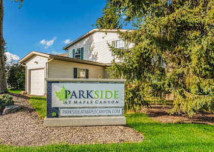 A sign for Parkside at Maplecanyon in front of a house.