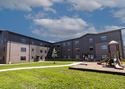 A playground area is located in front of a modern building.