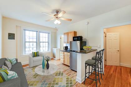 a living room with a kitchen and a ceiling fan