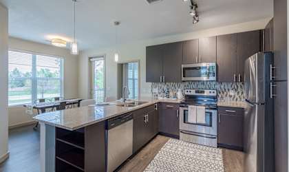 an open kitchen with stainless steel appliances and a granite counter top