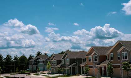 A row of houses with a blue sky and clouds in the background.