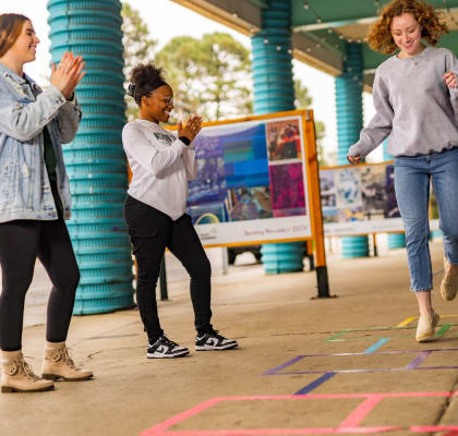 three young women playing hopscotch on a sidewalk