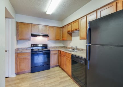 a kitchen with wooden cabinets and a black refrigerator
