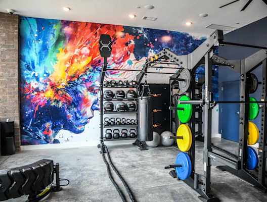 A gym with a large mural on the wall and various exercise equipment.