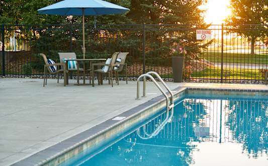 A pool with a blue umbrella and chairs around it. at The Winhall of Williams Pointe Apartments, Waukee