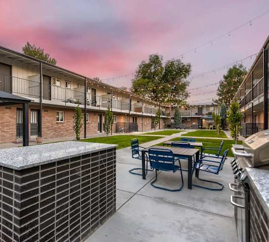 A sunset view of a patio with tables and chairs.