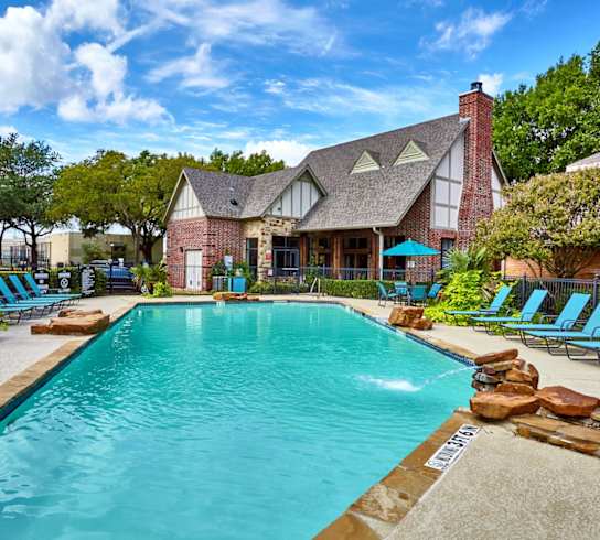 A large swimming pool with Fusion Crossroads Apartments leasing office in the background.