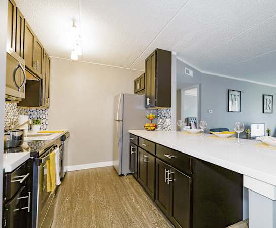 A modern kitchen with a white countertop and stainless steel appliances.