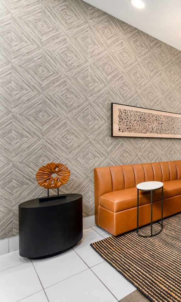 A modern office lobby with a large orange sofa and a patterned wallpaper.