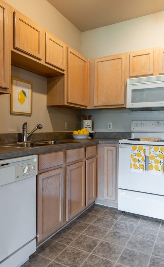 a kitchen with white appliances and wooden cabinets  at Stonepost Lakeside Apartments , Kansas , 66103