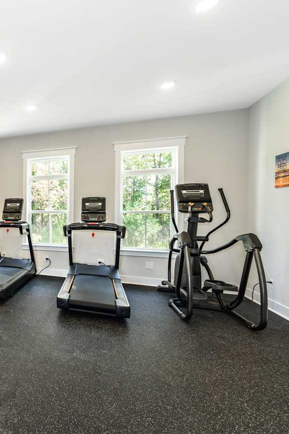 A gym with treadmills, elliptical machines, and dumbbells at The Promenade at Easton Apartments, Easton