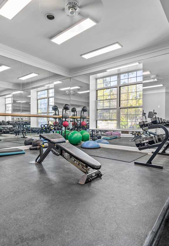 A gym with various exercise equipment and a mirrored wall.