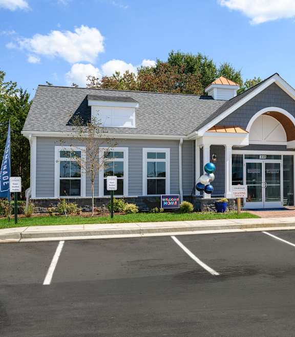 A building with a grey roof and white walls with a parking lot in front at The Promenade at Easton Apartments, Maryland, 21601