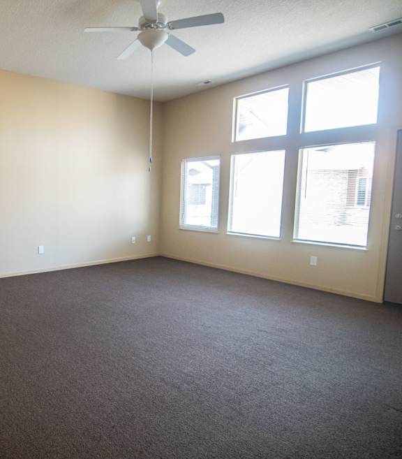 Empty room with a ceiling fan and three windows.at Cottages at Johnston Commons, Johnston Iowa