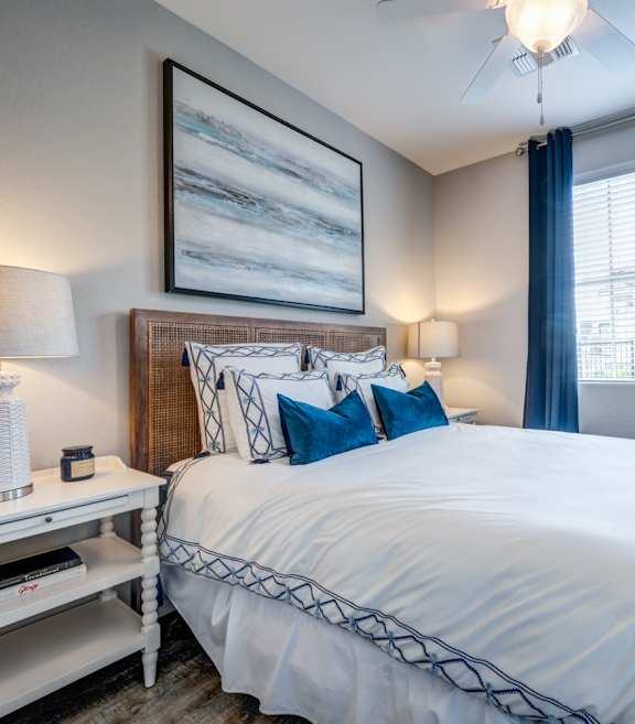 A bedroom with a bed, nightstand, and a plant.