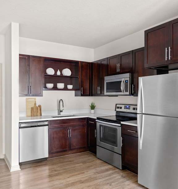 A kitchen with a refrigerator, oven, and sink.