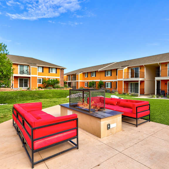 Furnished patio with red couches and fire pit at Indigo Apartments 