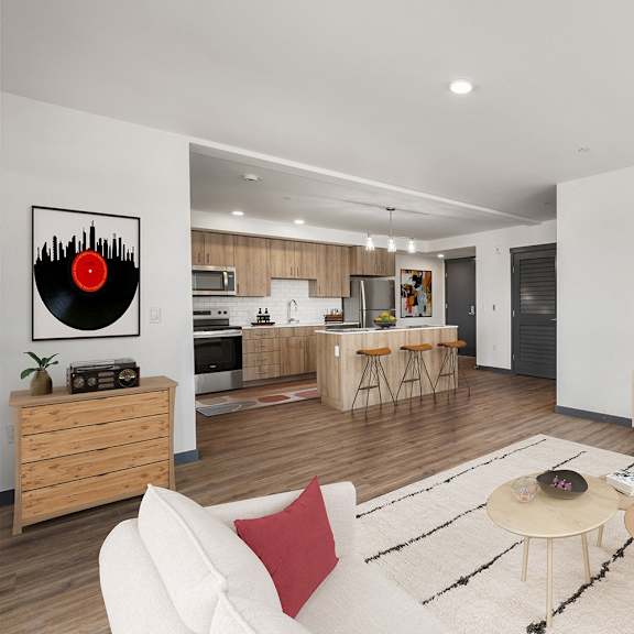 Elevation16 apartment living area with a couch, tables, wall mounted tv and kitchen bar in the backgroundd