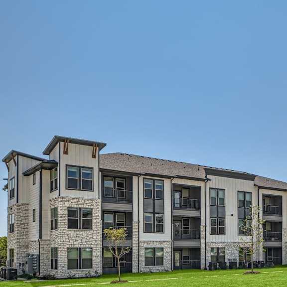 A large apartment complex with multiple buildings and green lawns in front.