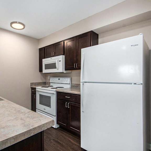 a kitchen with white appliances and dark wood cabinets