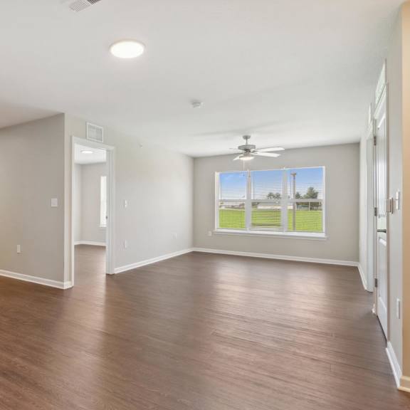an empty living room and kitchen with wood flooring