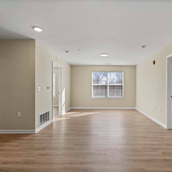 an empty living room with wood floors and a window