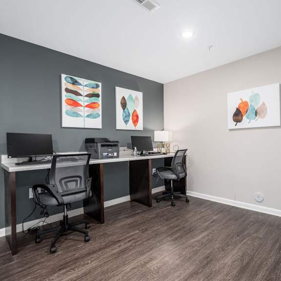 a home office with two desks and two chairs and paintings on the wall