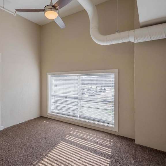 A room with a ceiling fan and a window with blinds.