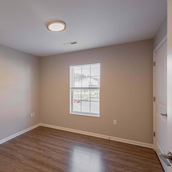 an empty living room with a white door and a window