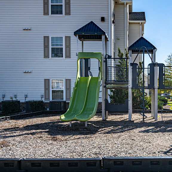 A playground with a green slide and a blue roofed structure.