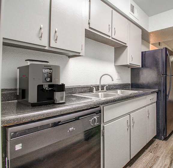 A kitchen with a refrigerator, sink, and stove.