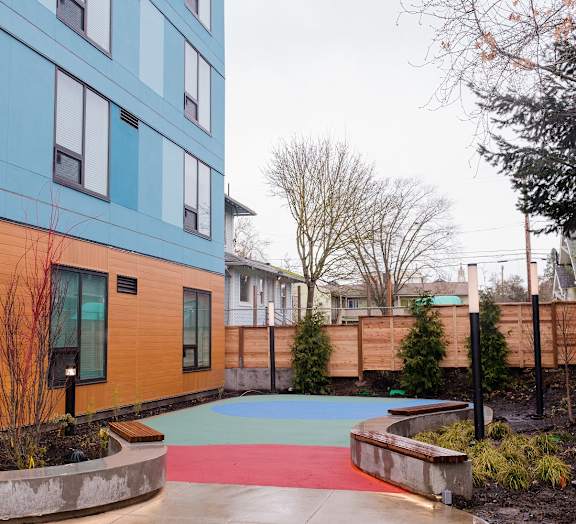 A playground area with a slide in front of a building.
