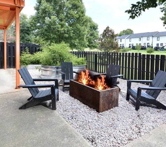 a patio with a fire pit and chairs and a black fence at Capital Flats & Magnolia Square Apartments, Raleigh, NC
