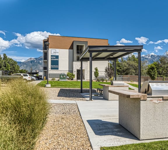 a picnic area with a grill and a building with mountains in the background