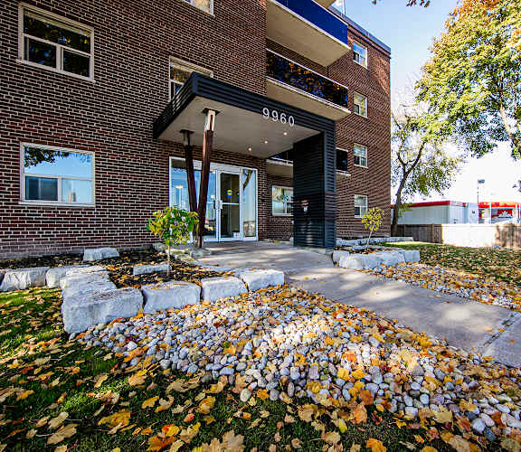 a large brick building with a black awning and a pile of leaves on the ground