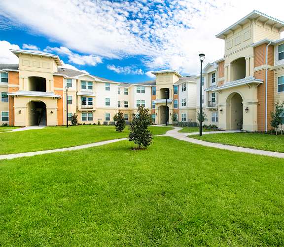 a grassy area with walkways in front of an apartment building