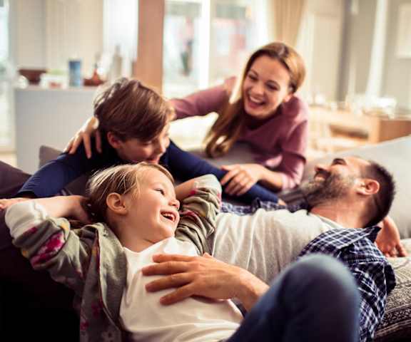 A family of four is relaxing on a couch together.