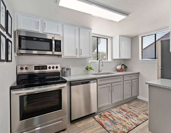 an open kitchen with stainless steel appliances and white cabinets