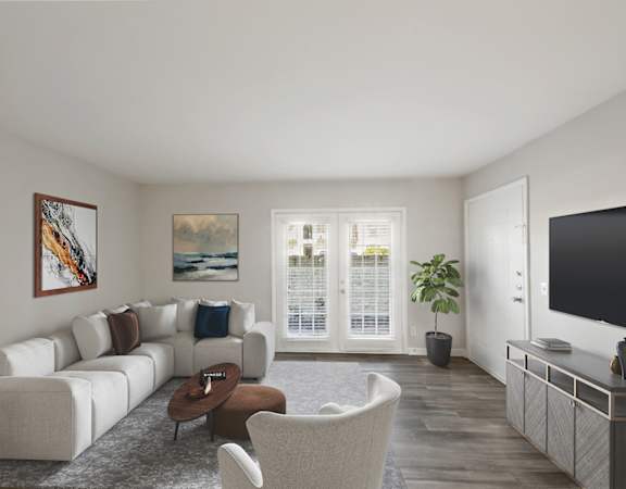 Apartments in Sandy Springs Georgia for Rent – Celebration at Sandy Springs - A living room with a white couch, a brown chair, a coffee table, a television, and a painting on the wall.